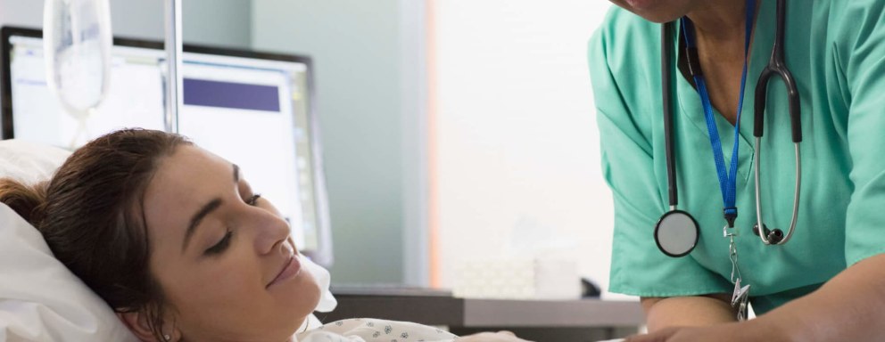 A black female nurse midwife massages a pregnant patient's belly while she's in labor