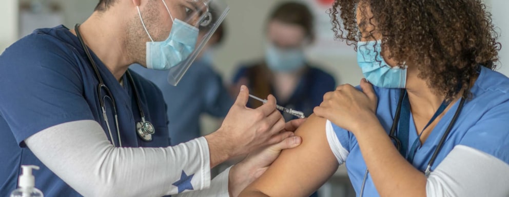 African-American female nurse receiving the COVID-19 vaccine