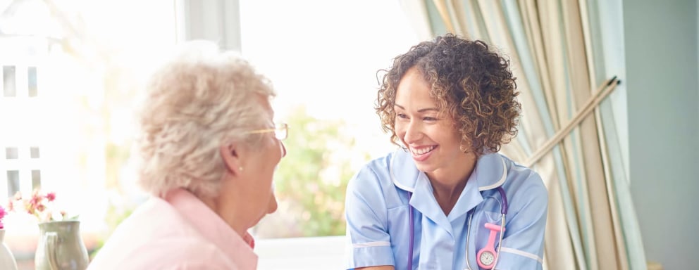 A senior woman in her home laughing with hospice nurse