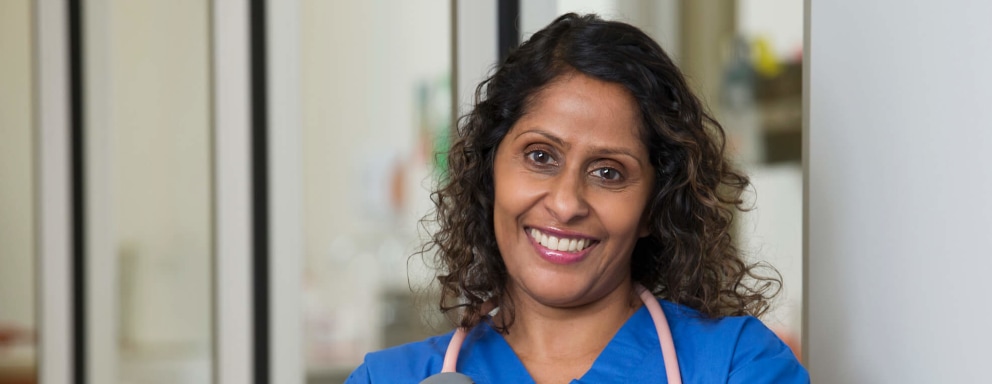 Female Indian-American nurse smiling while standing in a hospital lobby