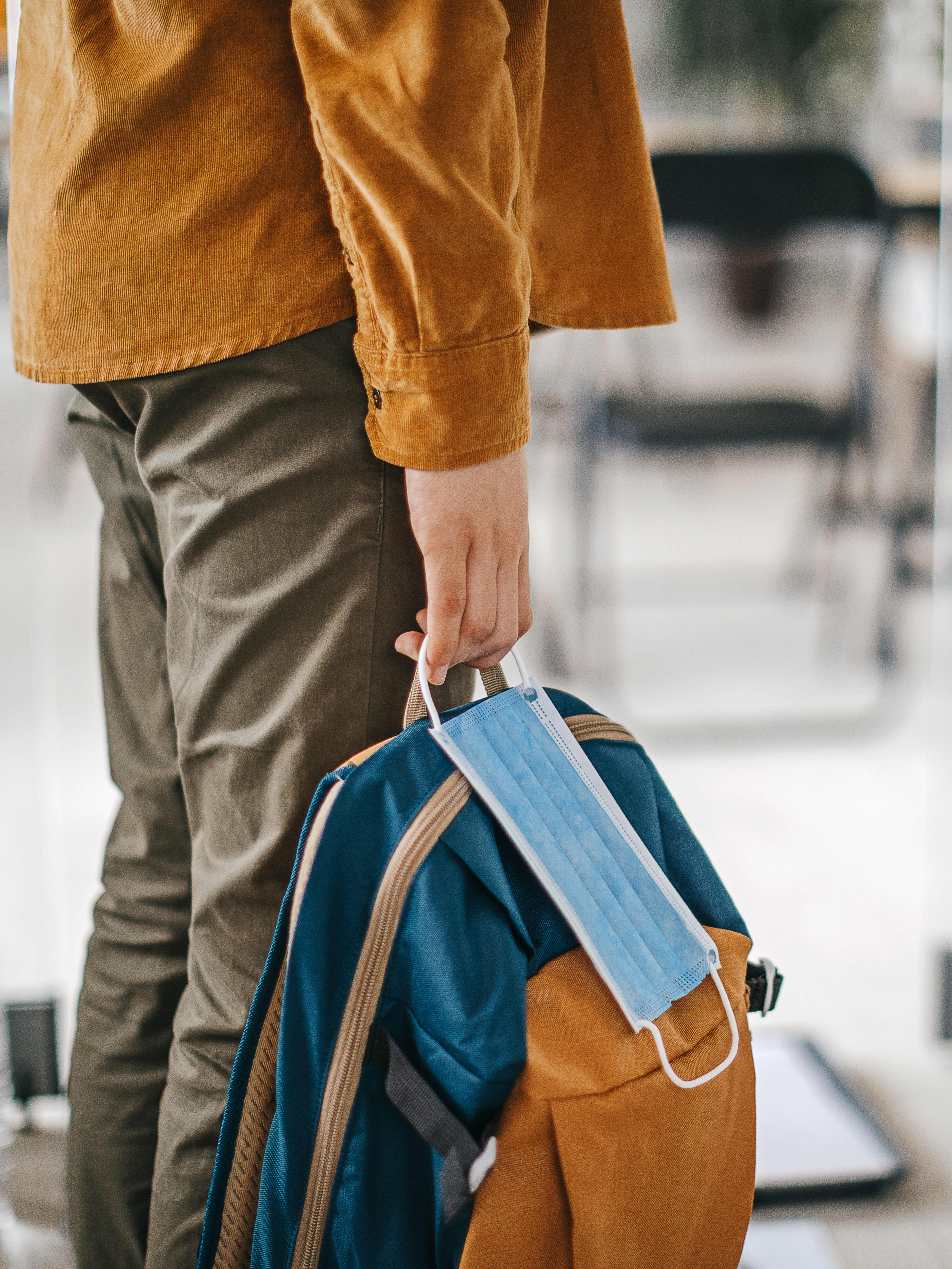 Image of person holding a backpack and mask