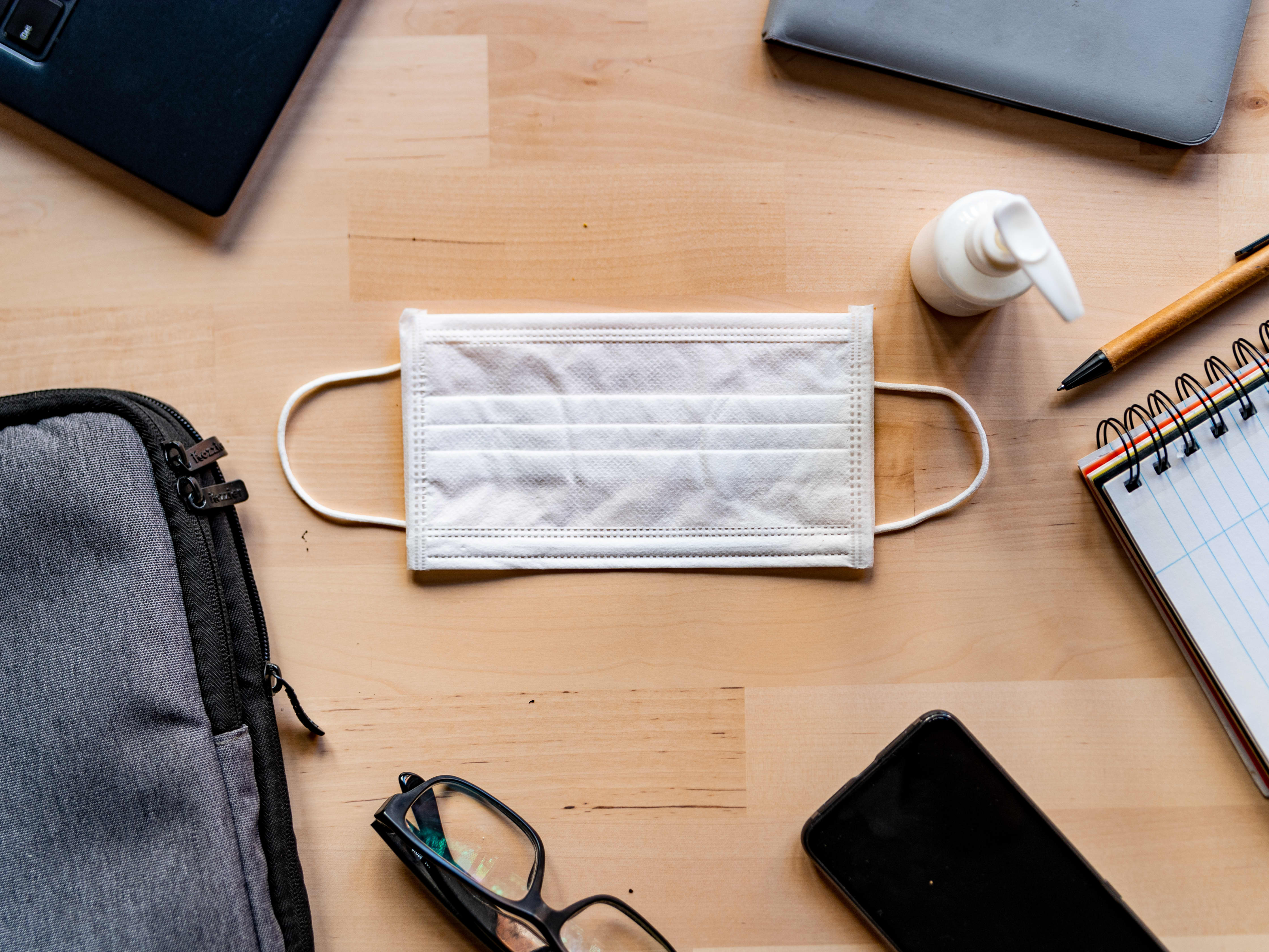 Flat lay image of mask, hand sanitizer, and school supplies