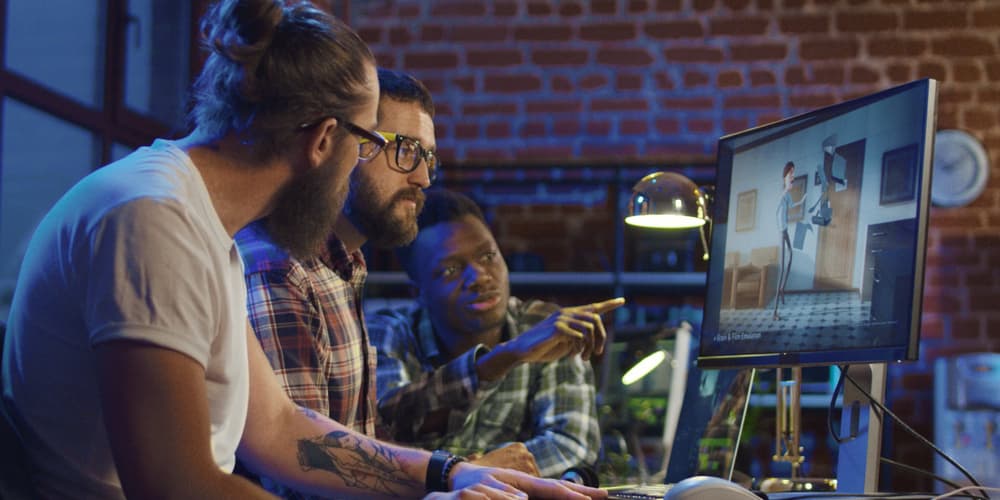 Image of three animators discussing an animation project in front of a computer