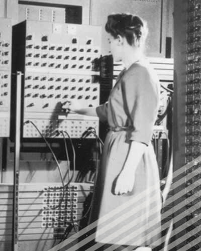 One of the ENIAC programmers adjusts a knob on an enormous early computer.