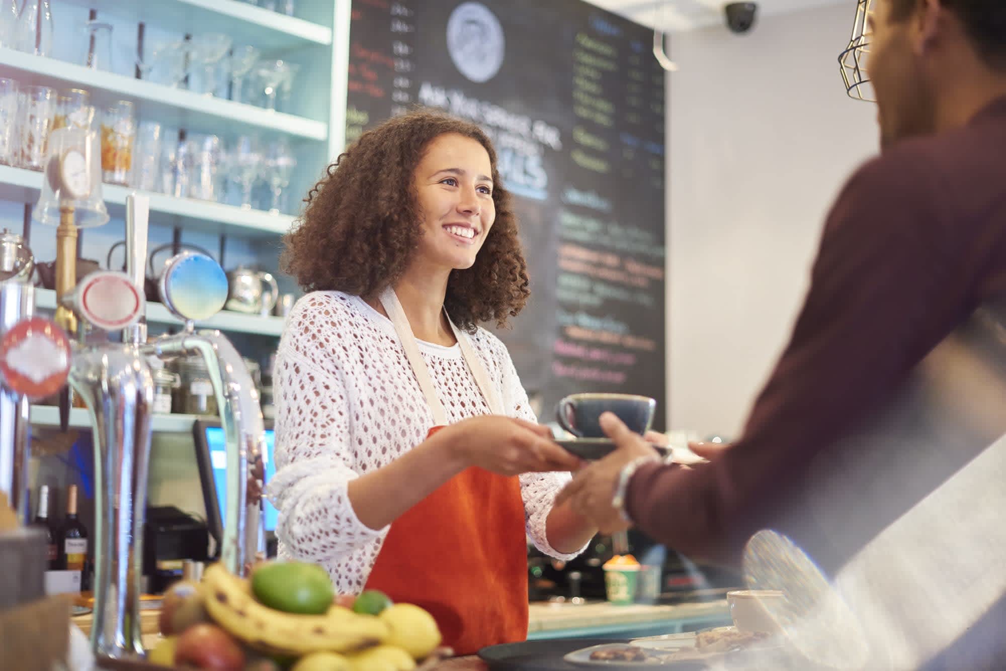 A smiling barista serves coffee to a customer