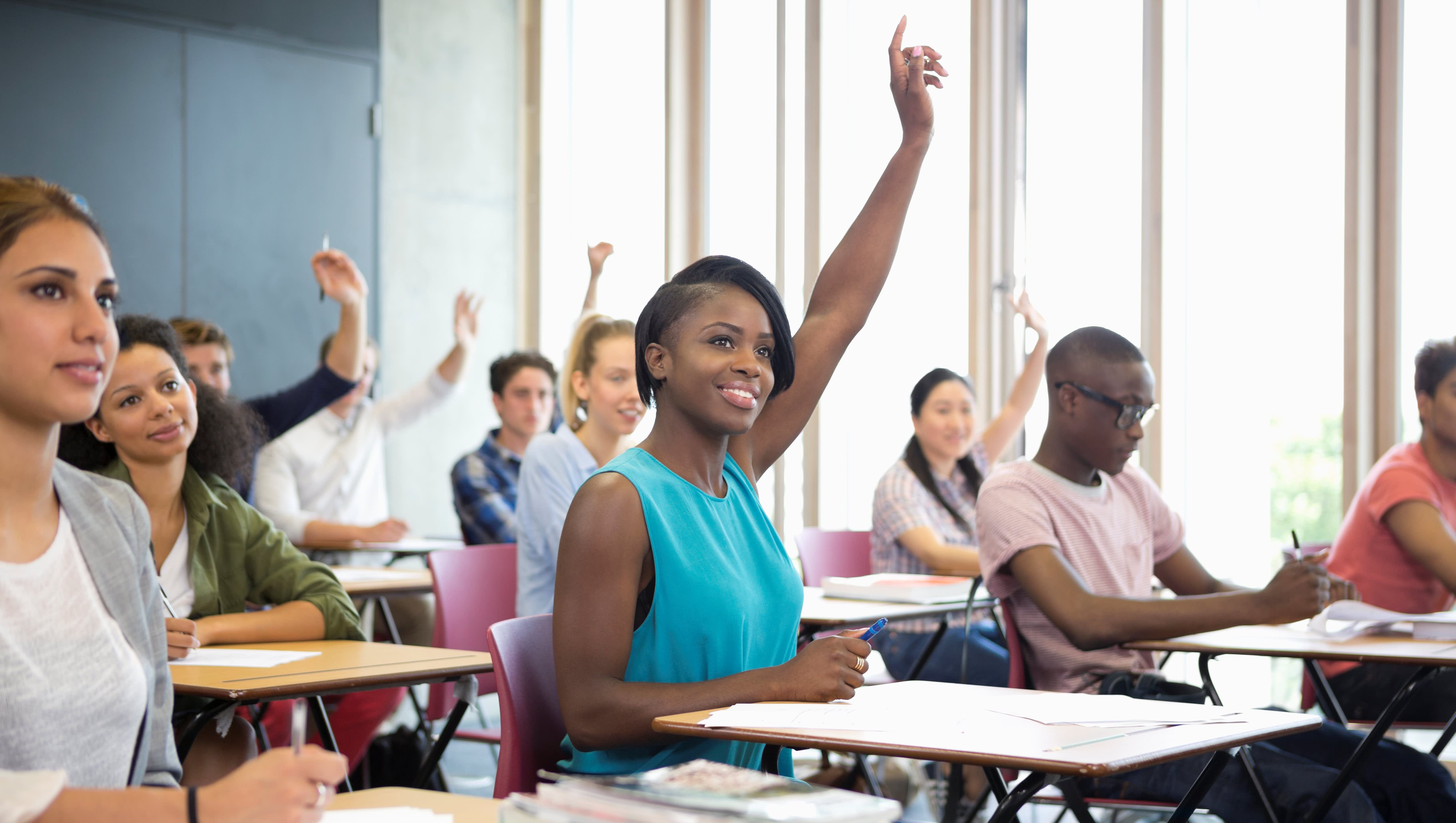 A college student raises her hand in class