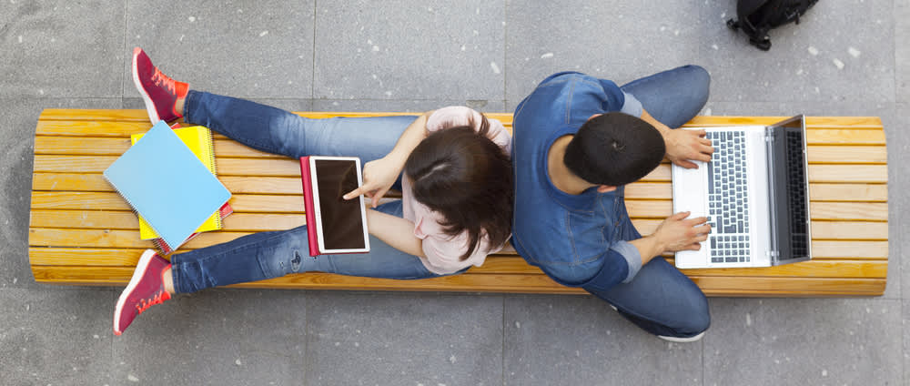 college students on bench with laptops