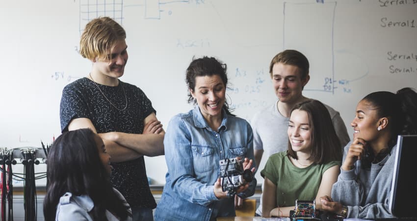 A teacher explains a mechanical concept to students in a classroom