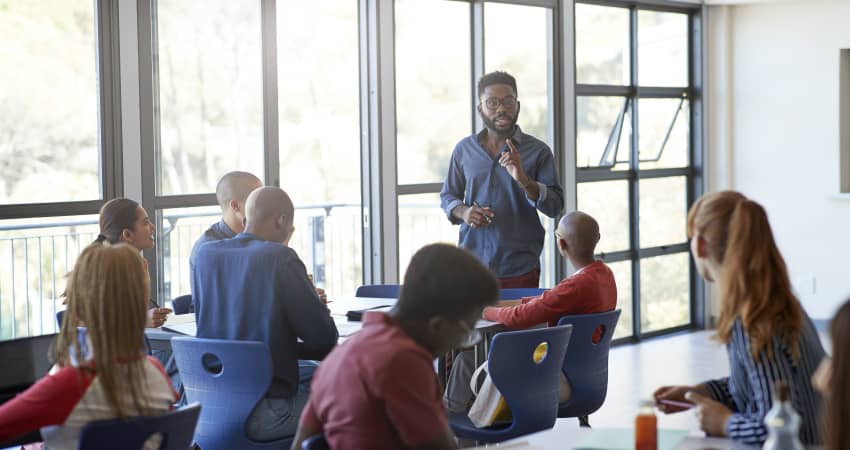 A professor stands in front of the class, delivering a lecture