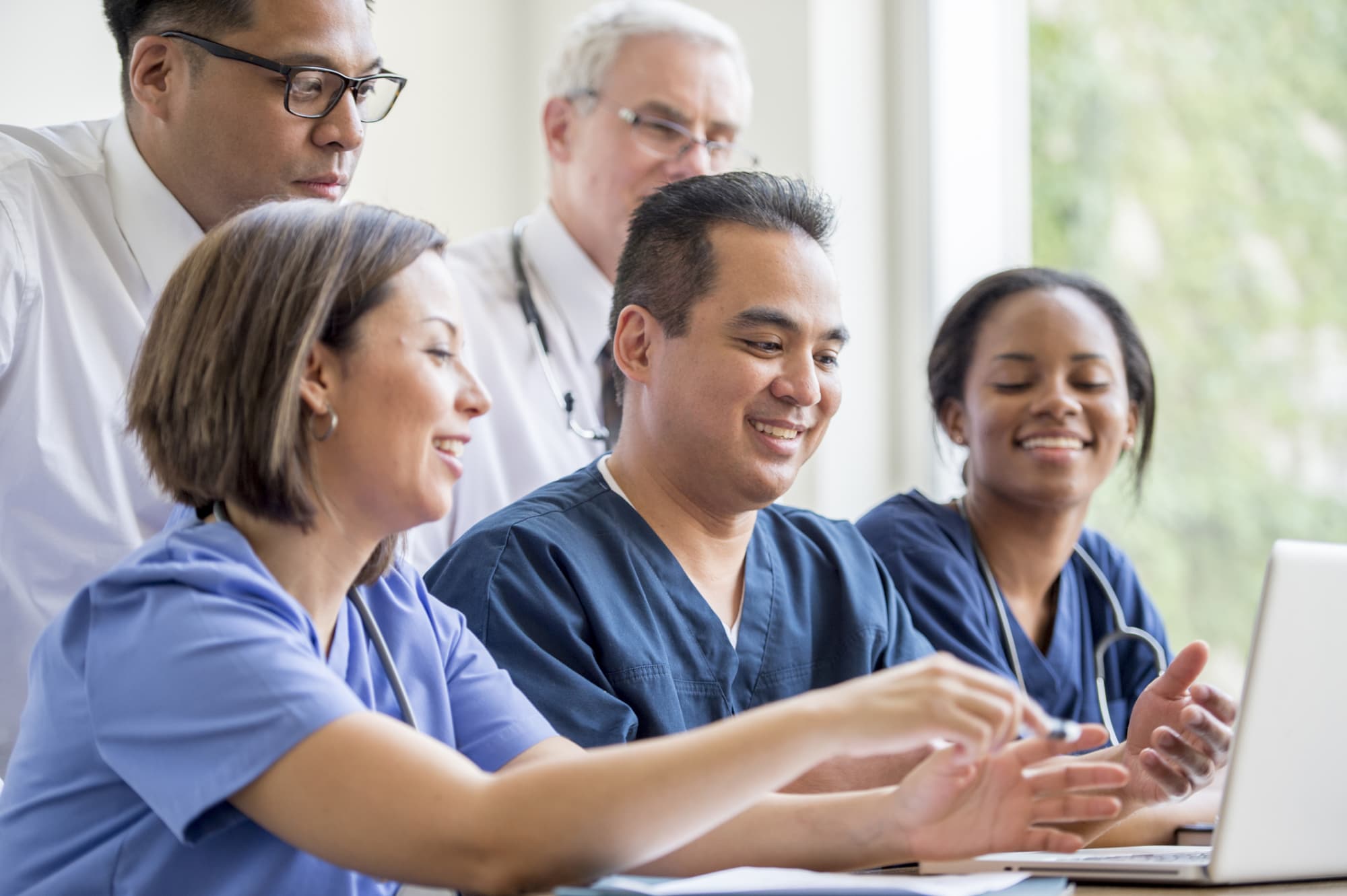 A multi-ethnic group of hospital nurses and staff researching a new procedure.