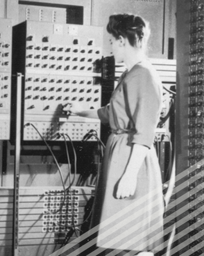 One of the ENIAC programmers adjusts a knob on an enormous early computer.