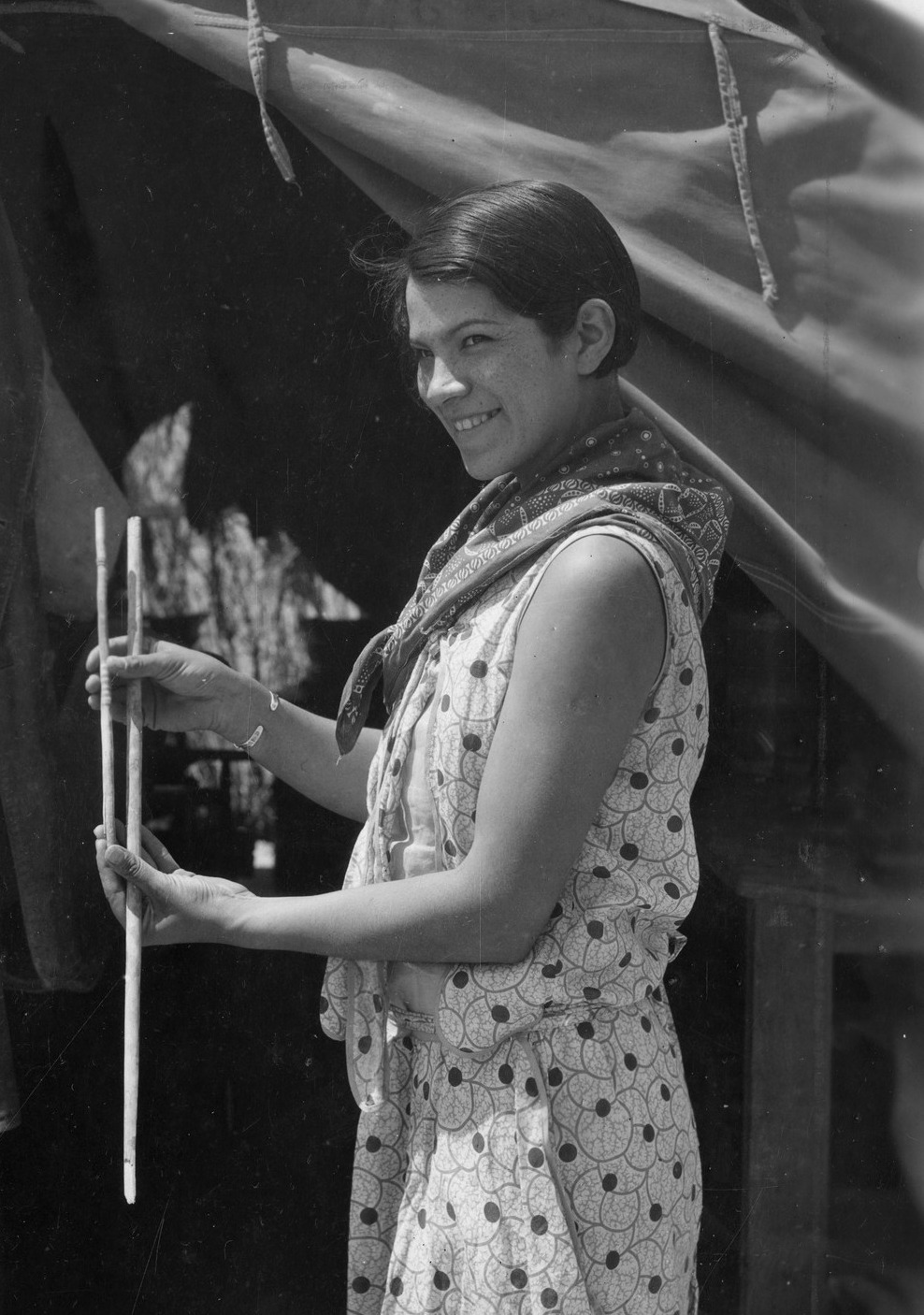 A black and white photograph depicts a young Bertha Parker Pallan Cody holding atlatl darts.
