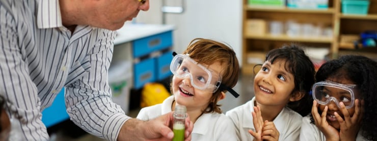 Male teacher working with three attentive elementary school students