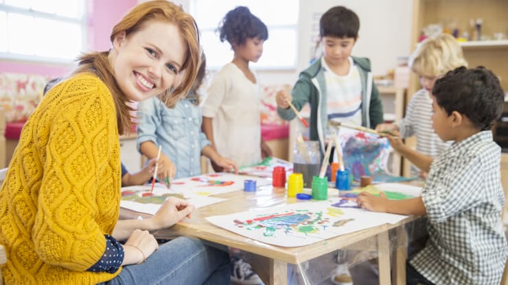 The Most Affordable Online Bachelor's in Early Childhood Education Degree Programs Hero Image: The Most Affordable Online Bachelor's in Early Childhood Education Degree Programs (A teacher working with their students on a painting project)