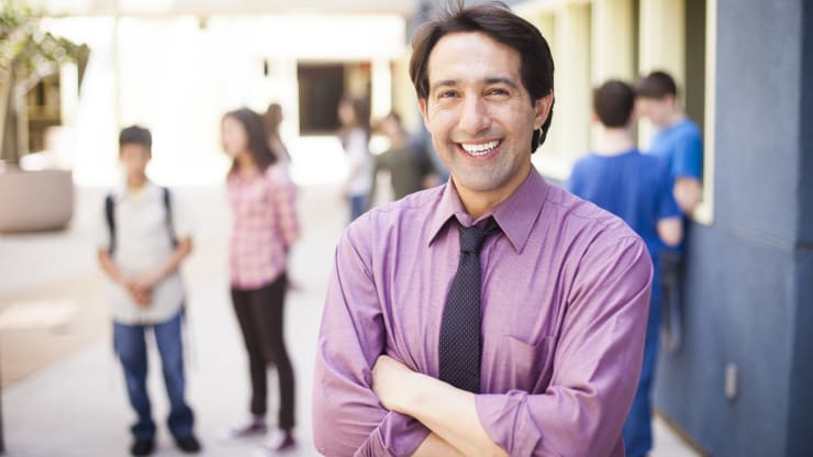 The Most Affordable Online Master's in Educational Leadership Degree Programs Hero Image: The Most Affordable Online Master's in Educational Leadership Degree Programs (A principal stands outside of their school with students in the background)