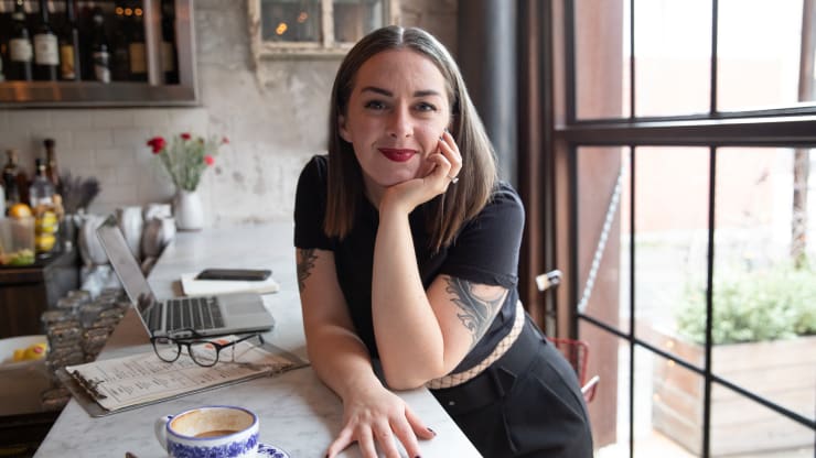 The Most Affordable Online Bachelor’s in Hospitality Management Degree Programs Hero Image: The Most Affordable Online Bachelor’s in Hospitality Management Degree Programs (Image of a restaurant owner in their restaurant working on a laptop)