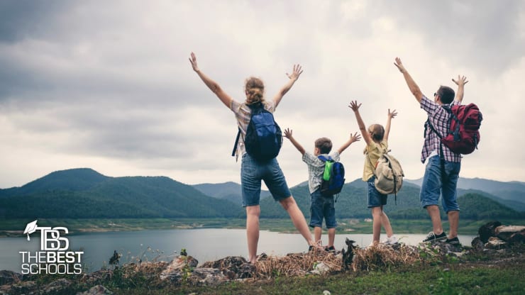 Best Online Bachelor's in Human & Family Development Programs: People on a hill overlooking a bay with their arms raised over their heads.