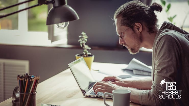 The 10 Best Online Bachelor's in Web Development Programs Hero Image: The 10 Best Online Bachelor's in Web Development Programs (Image of white man with ponytail working on a laptop)
