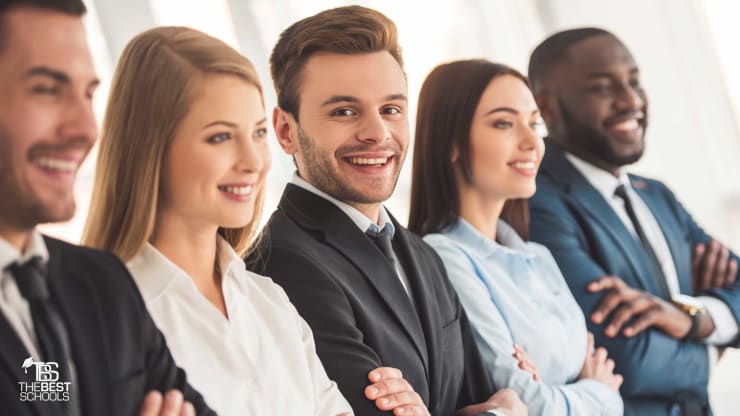 Best Online Masters in Management Hero: Five young buisness people are standing in a line. Two are white men, two are white women, and one is a black man. The camera is focused on the central white man.