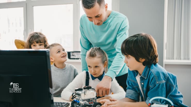 Hero Image: The 30 Best Online Master’s in Curriculum and Instruction Degree Programs (teacher with young students, robotics, computer, tech)