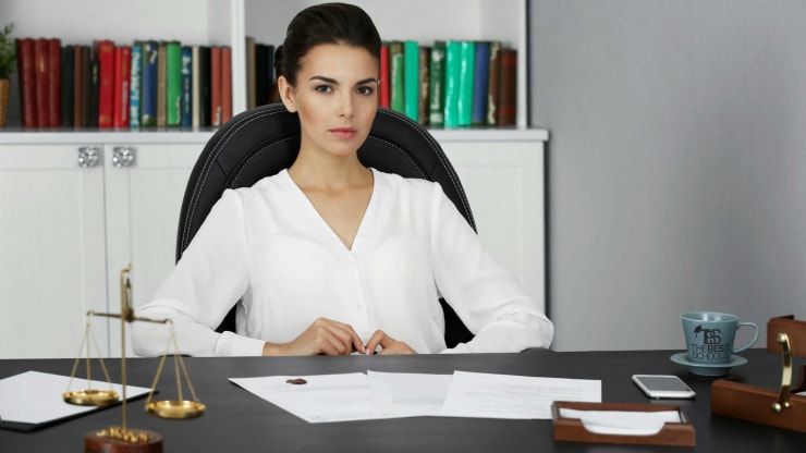 Young behind desk with scales of justice in foreground