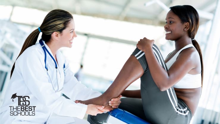 Best Online Master’s in Sports Medicine Programs Hero Image: White, female doctor treating a black, female athlete on a doctor’s table