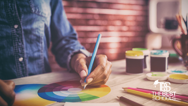 Hero Image for What Can You Do With a Degree in Art & Design?: Chest and hands shot of black person at design desk working on a color wheel.