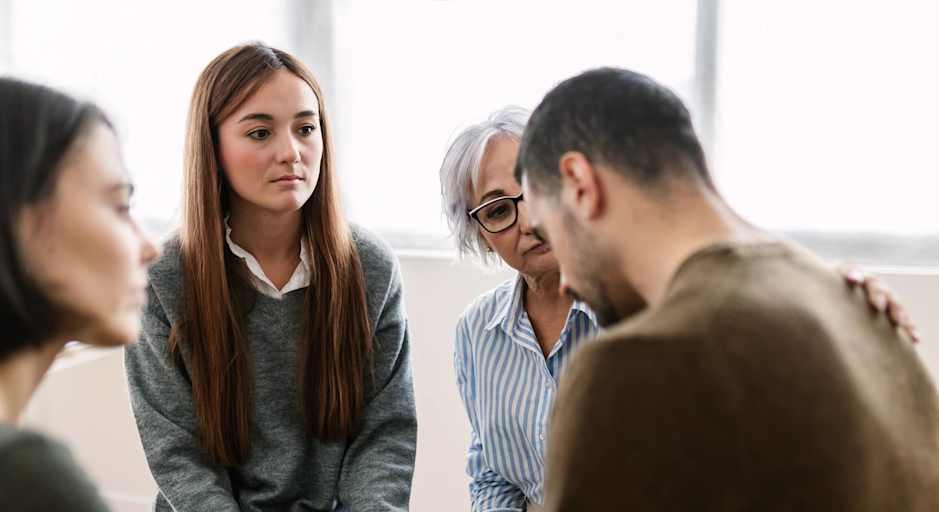 Counselor and peers being supportive to man in group counseling session
