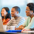 A multi-ethnic group of college students are sitting in a lecture hall and are working on a homework assignment for a group project.