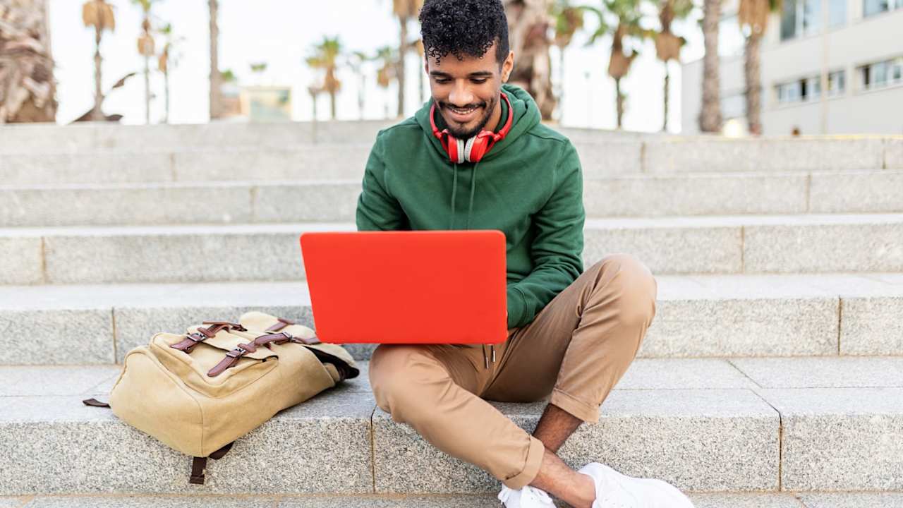Student sitting outside on stairs and typing on laptop