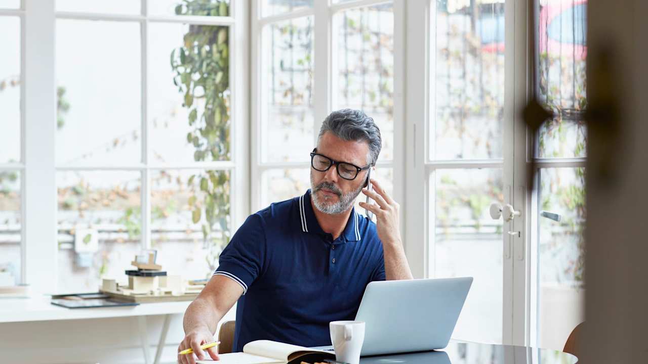 Man talking on phone and working on laptop
