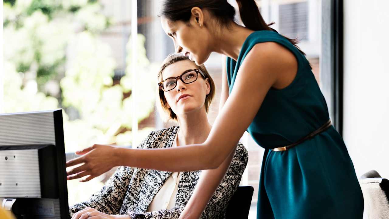 Two women working together on a computer in an office