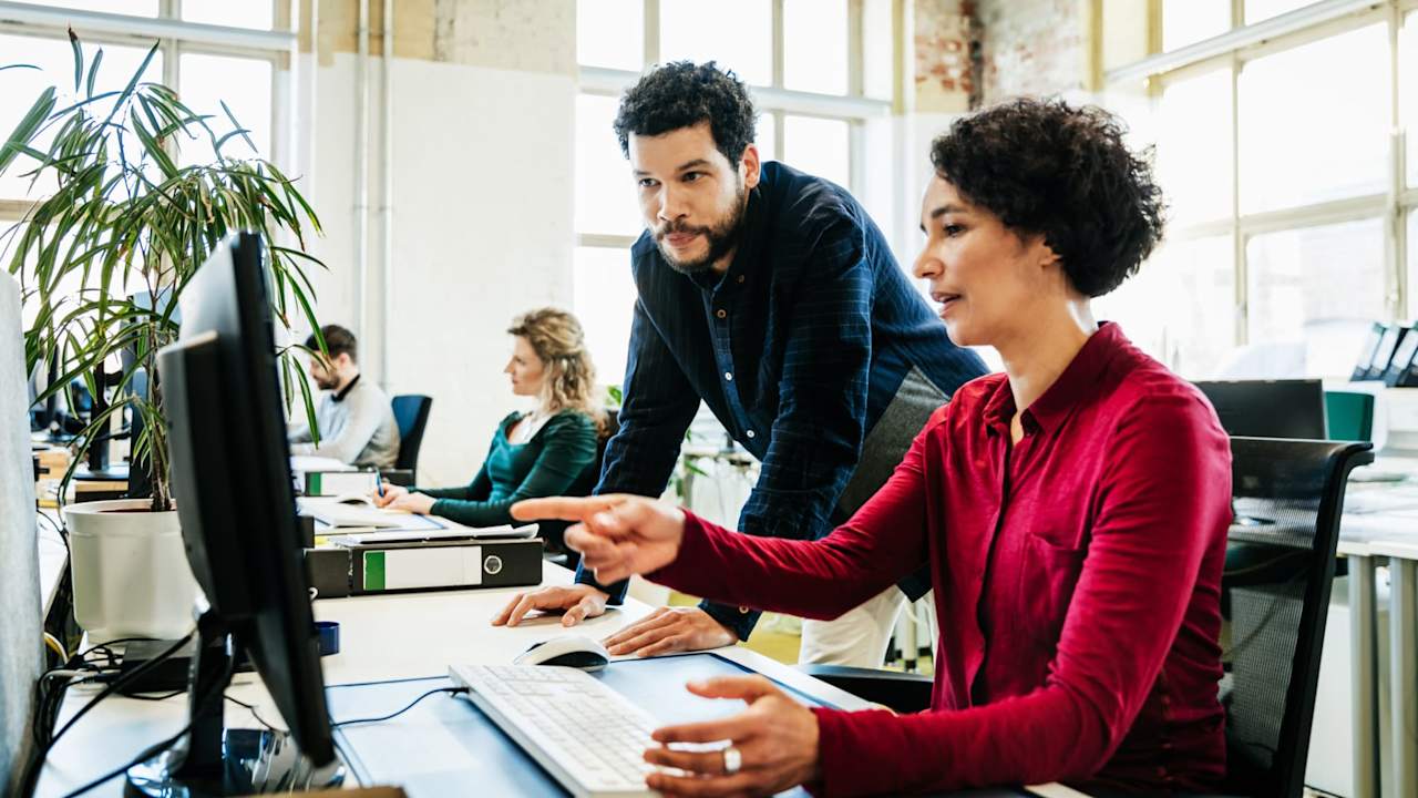 Woman being helped by coworker on computer