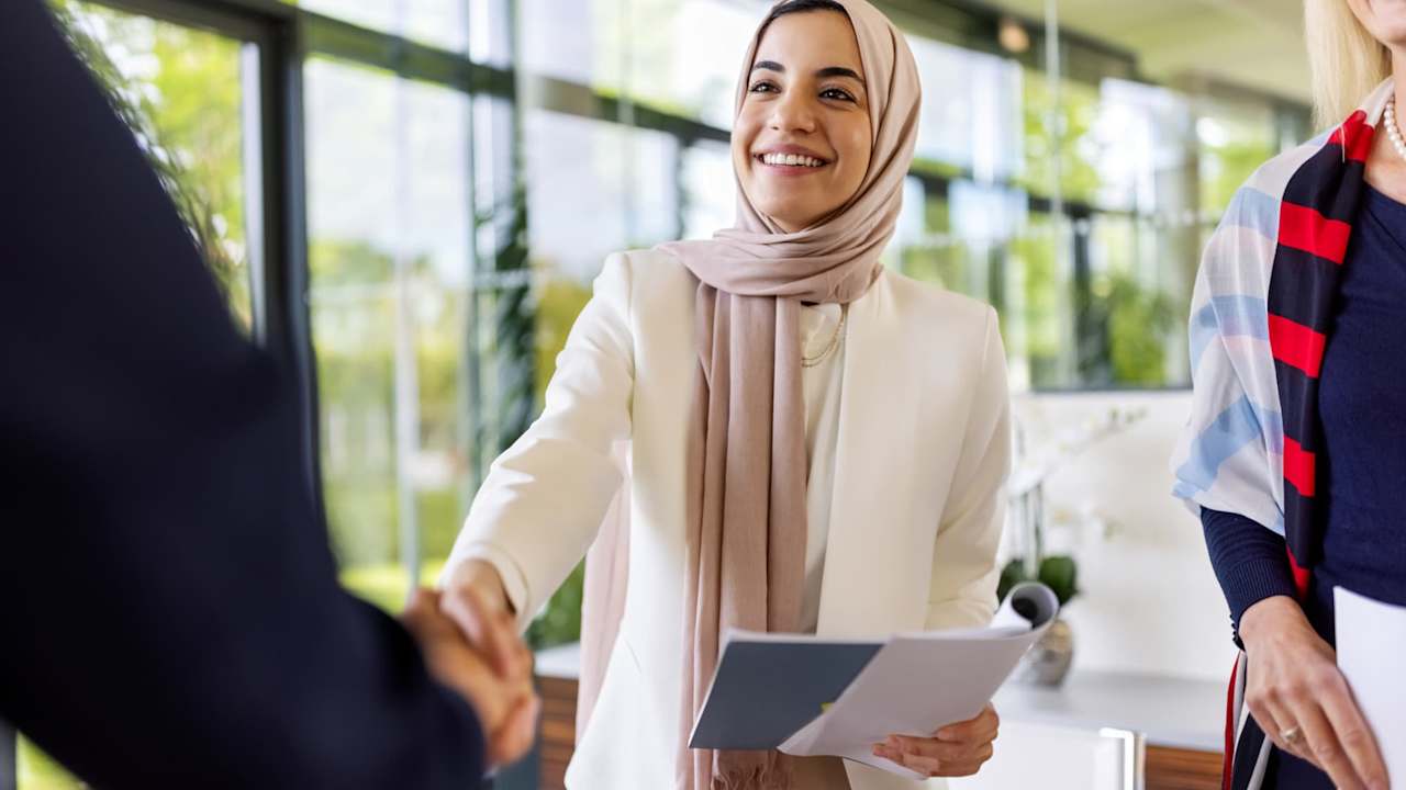 Young woman shaking hands with her new business partner after a successful deal. Business people sealing a deal with a handshake.