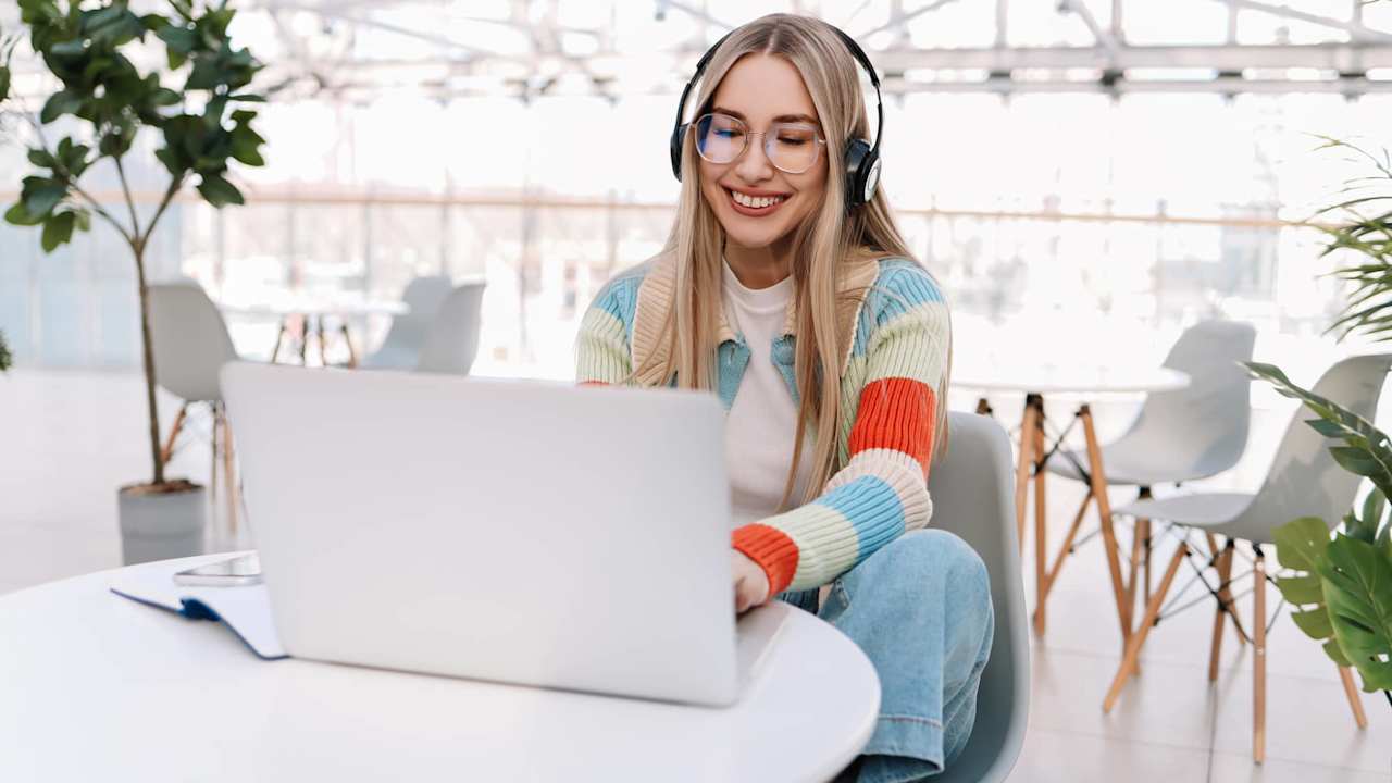 Young woman working on laptop wearing headphones