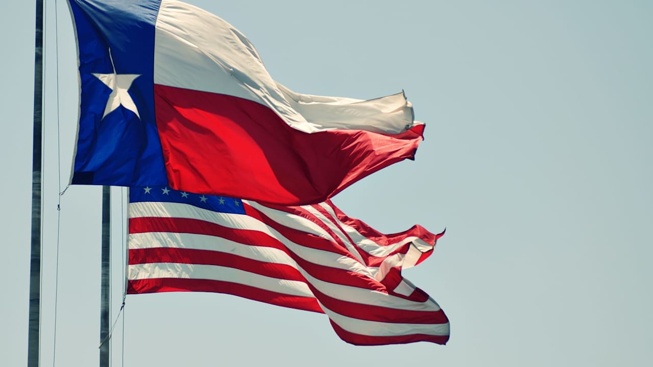 The Texas state flag in the wind next to the United States flag.