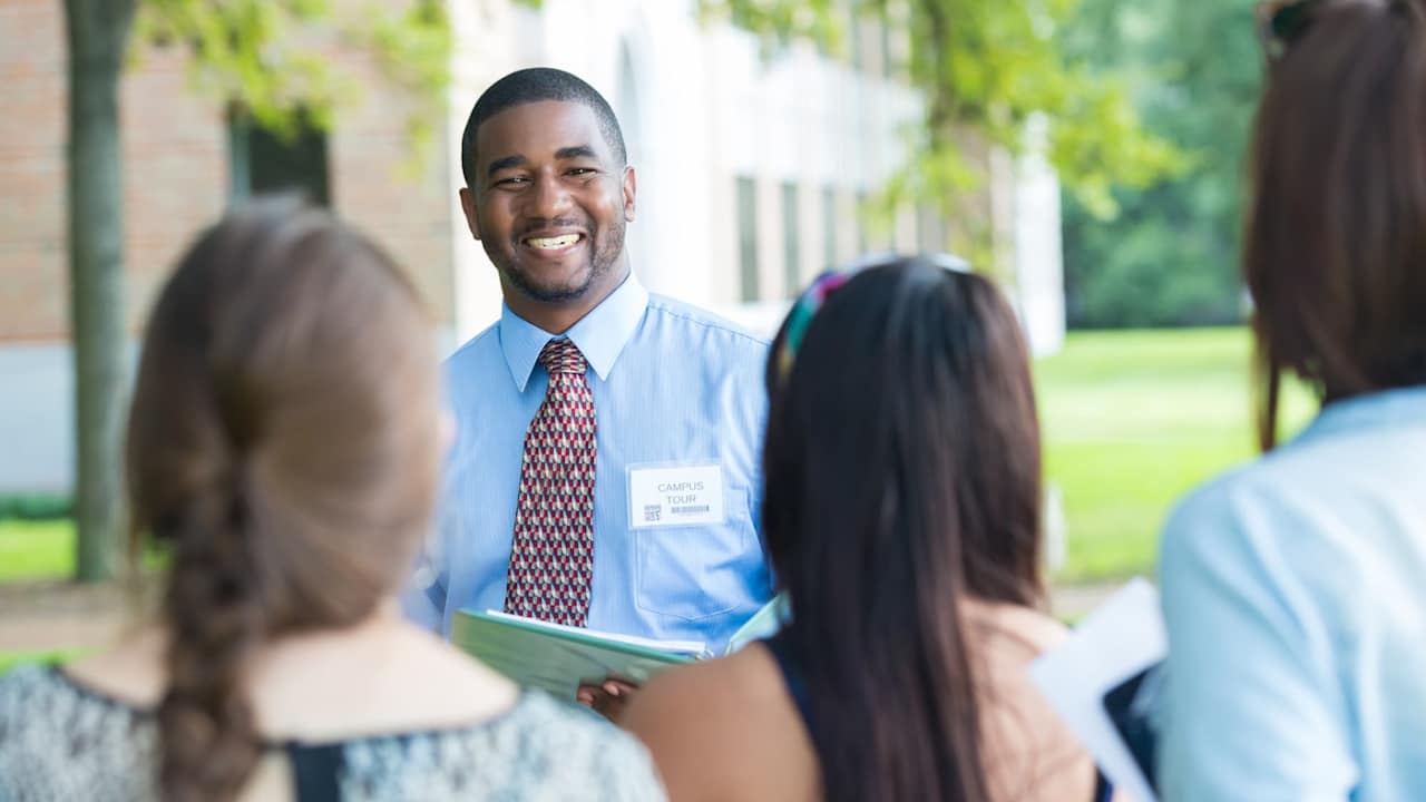 College campus tour guide talking with prospective students outdoors