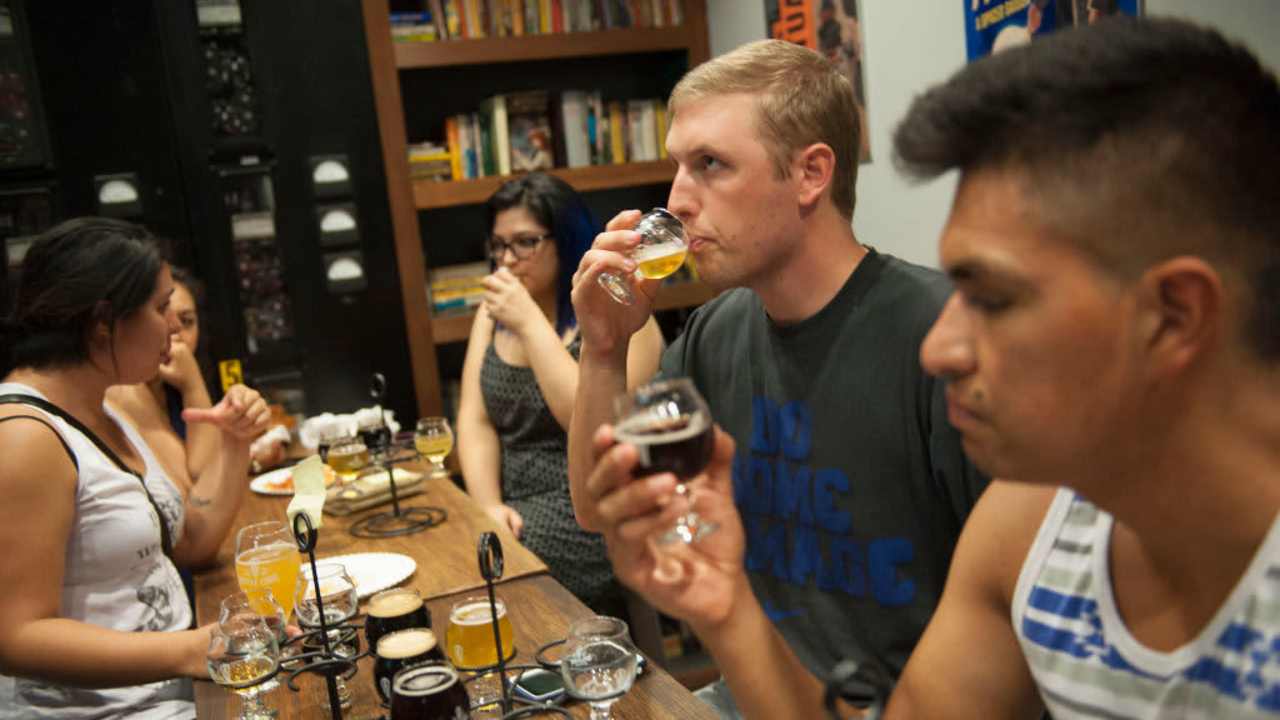 Geography major Cameron Isaac, 23, center, tastes a craft beer sample as Pedro Chacon, at right, examines a beer during a recent meeting of the Cal State Fullerton Craft Beer Advocacy and Home Brew Club at Bottle Logic Brewing in Anaheim.