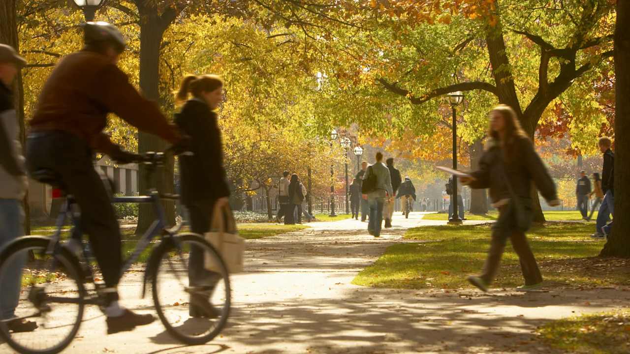 Students walking on footpaths on college campus, autumn
