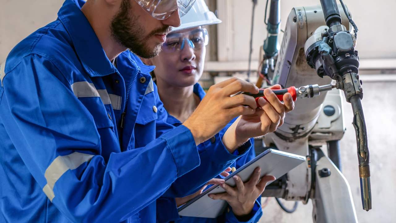 engineer repairing the robotic arm in a factory.