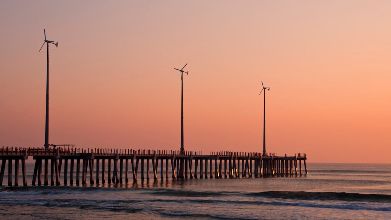 USA, North Carolina, Outer Banks, Kill Devil Hills, pier with wind turbines at sunset