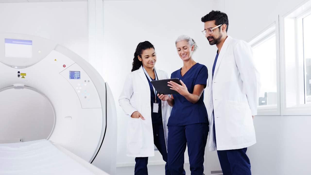 Nurses and doctor looking at a tablet, talking to each other