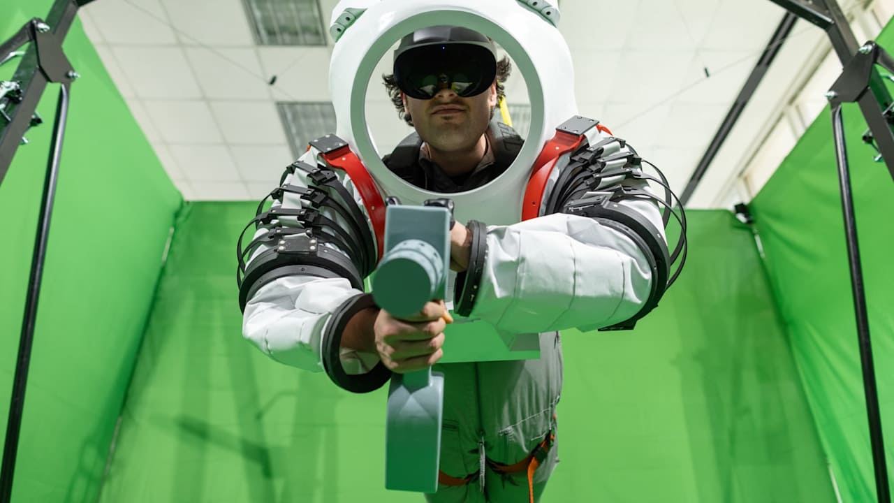 Mangili hanging from a crane in the mixed reality lab in his space suit