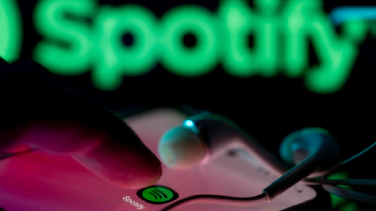 Person listening to Spotify app with Spotify logo in background