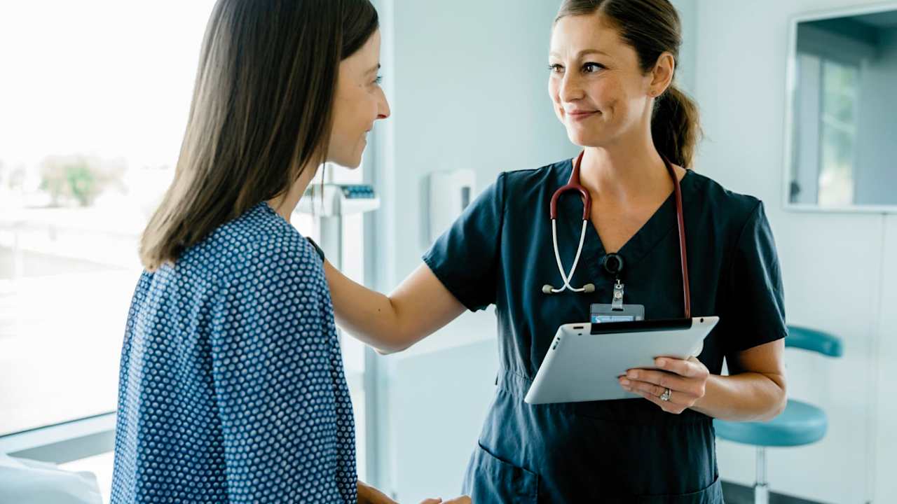 Nurse smiling at and helping a patient