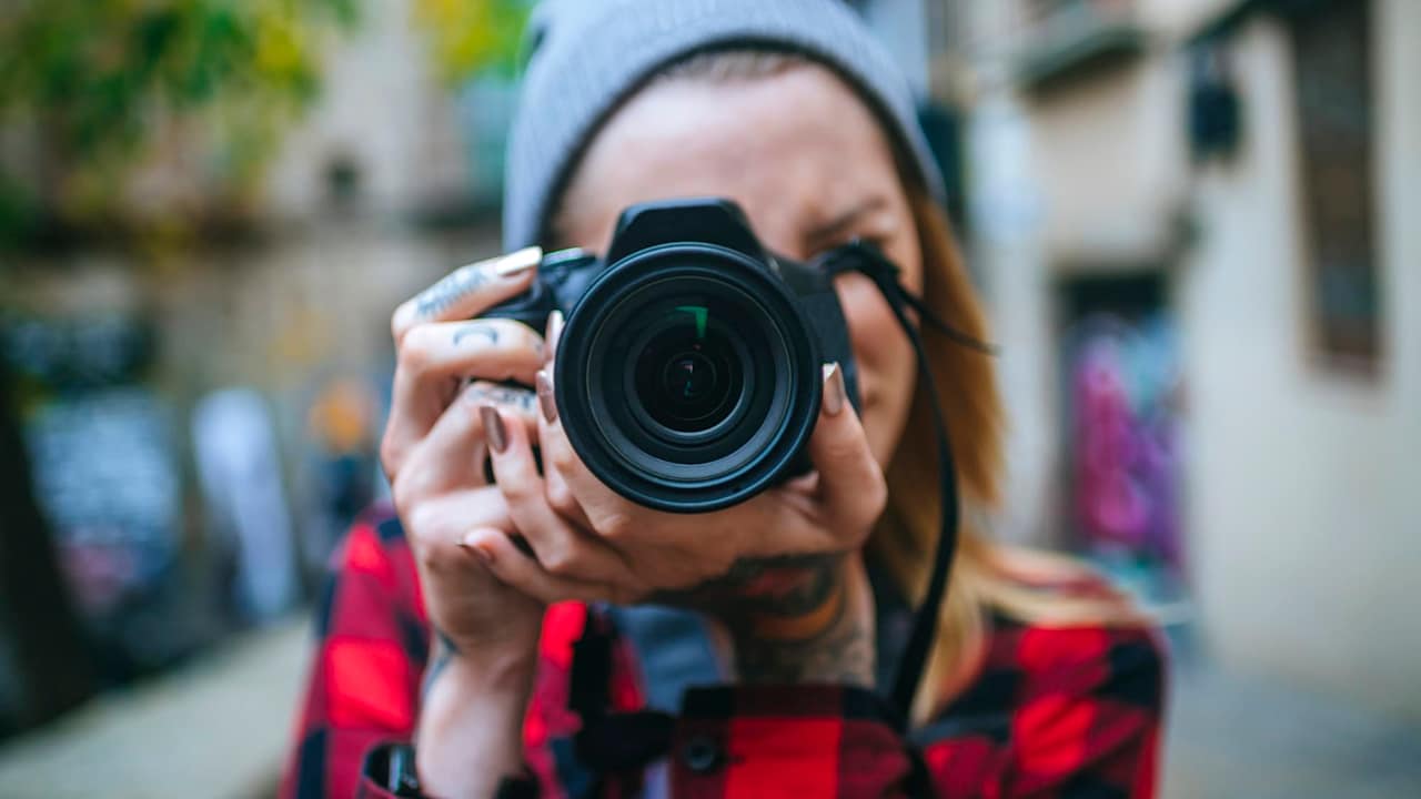 Female photographer taking a photo on a city street with a digital camera.