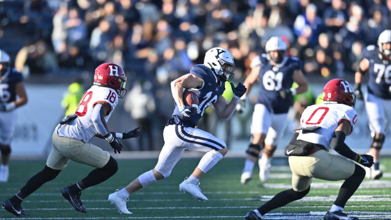 Football players on a field during a Harvard vs Yale game