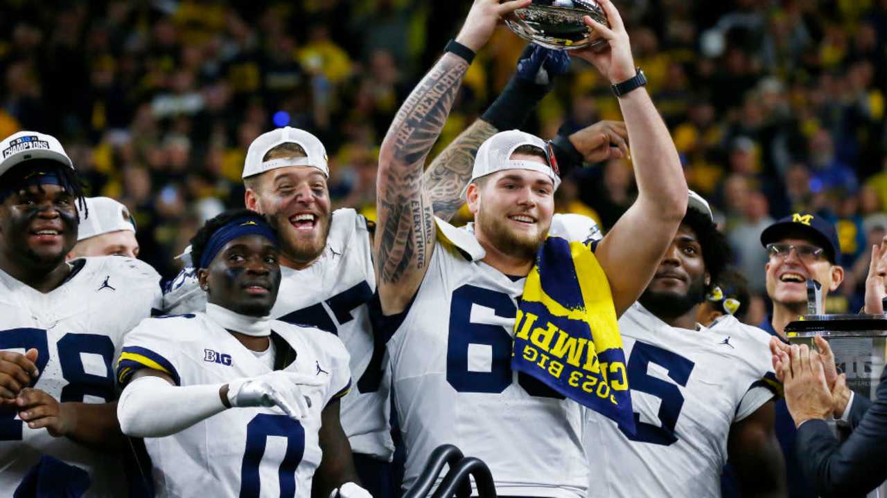 Michigan Wolverines offensive lineman Zak Zinter raises the championship trophy after Michigan wins the Big Ten Championship Game against the Iowa Hawkeyes on December 2, 2023, at Lucas Oil Stadium in Indianapolis, IN.
