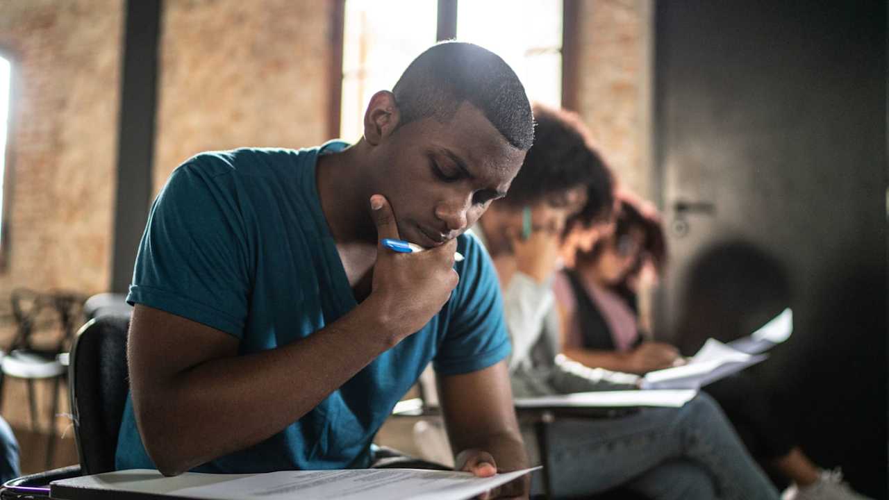 Black male student taking a standardized test in a university classroom.