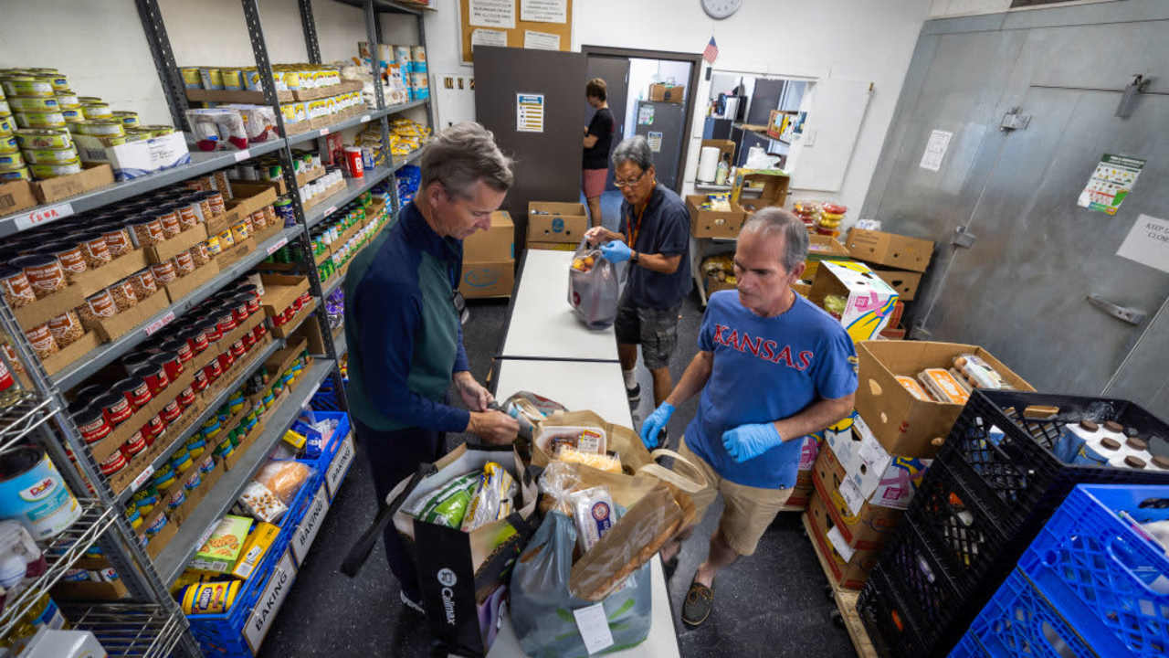 Patrick Dooley, Alex Skenderian, David Inouye, and Mike McGuinness pack bags of donated food to give to families at St. Margaret's Center in Inglewood, California. CalFresh benefits increased during the pandemic, but returned to non-emergency levels in spring of 2023.